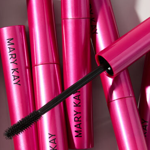 Hilera de tubos color rosa de r&iacute;mel con el logotipo negro Mary Kay colocados verticalmente con aplicadores de r&iacute;mel